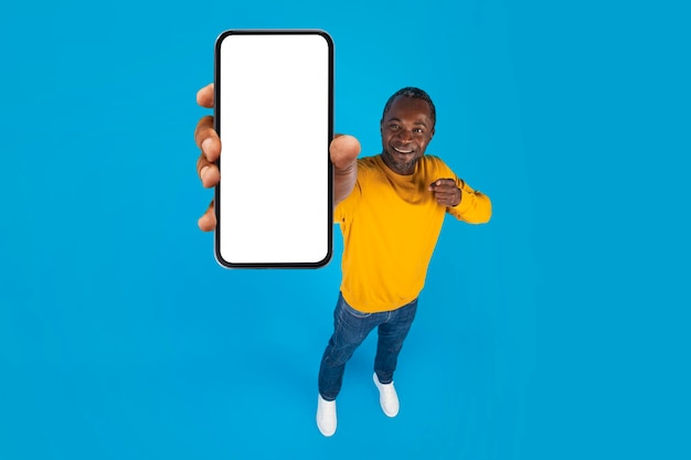 Uomo afroamericano felice che mostra il modello del telefono cellulare