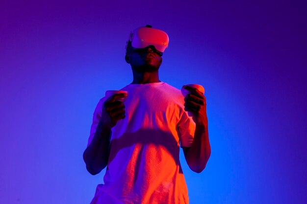 uomo afroamericano in occhiali di realtà virtuale tiene joystick in illuminazione al neon ragazzo giocatore