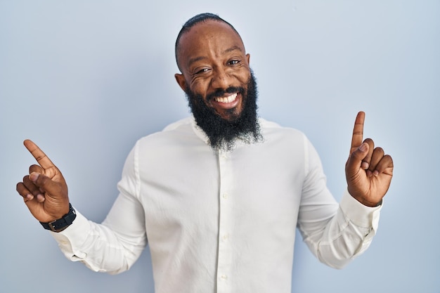 Uomo afroamericano in piedi su sfondo blu sorridente fiducioso che punta con le dita verso direzioni diverse copia spazio per la pubblicità