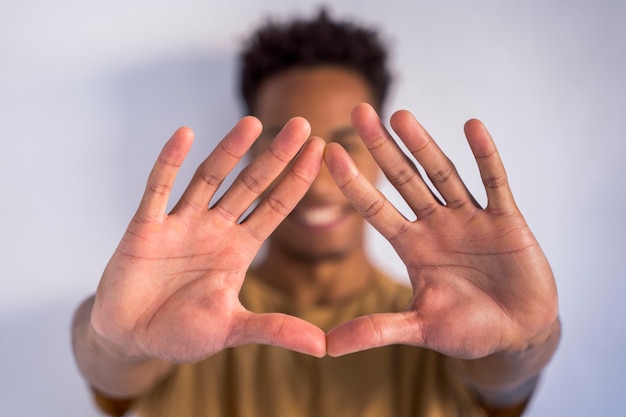 Uomo afroamericano irriconoscibile che fa una forma del segno del triangolo con le mani. Ferma il razzismo e abbraccia diverse etnie. Dettaglio delle mani spalancate insieme nella parte anteriore.