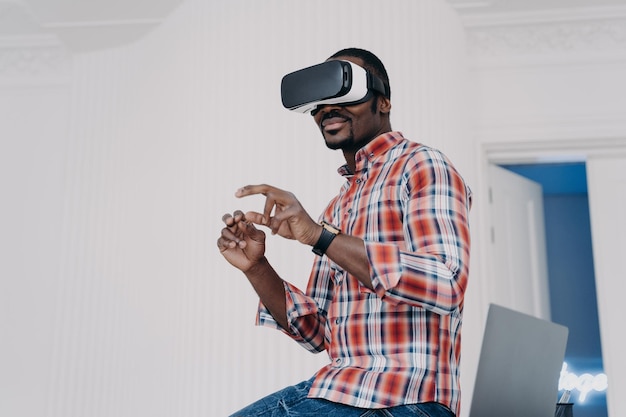 Uomo afroamericano moderno con occhiali per realtà virtuale godendo di un tour virtuale nel cyberspazio aumentato