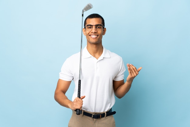 Uomo afroamericano sopra fondo blu isolato, giocare a golf e fare il gesto in arrivo