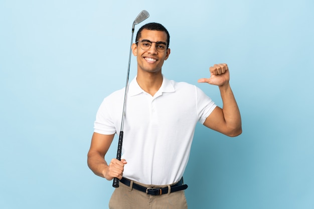 Uomo afroamericano sopra la parete blu isolata che gioca a golf e fiero di se stesso