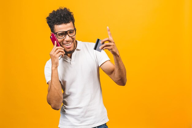 Uomo afroamericano vestito, utilizzando il telefono cellulare, mostrando la carta di credito in plastica.