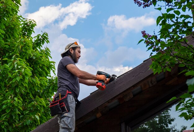 Uomo al lavoro sul tetto utilizzando un cacciavite elettrico