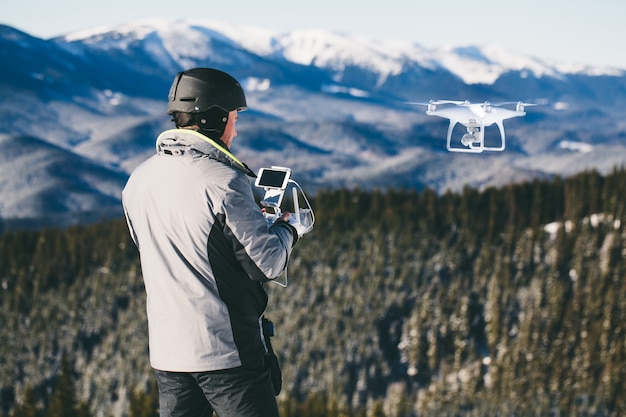 Uomo all'aperto con telecomando che pilota un drone in montagna