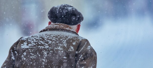 Uomo all'aperto in abiti invernali durante la bufera di neve e forti nevicate