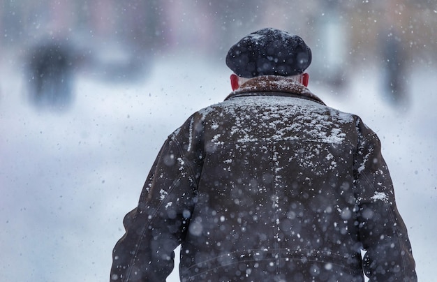 Uomo all'aperto in abiti invernali durante la bufera di neve e forti nevicate