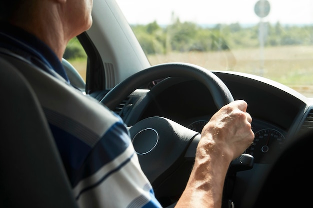 Uomo alla guida di auto, primo piano. Mani del conducente che tengono il volante di un'auto.