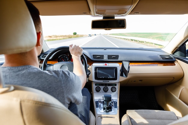 Uomo alla guida di un'auto moderna su strada asfaltata