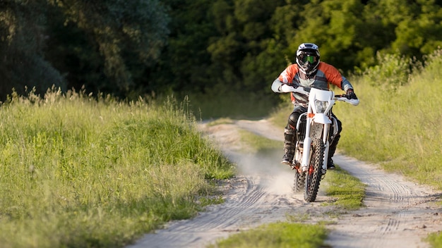 Uomo alla moda che guida una motocicletta nella foresta