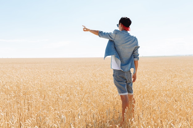 Uomo alla moda con gli occhiali da sole nel campo di grano