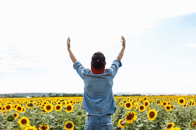 Uomo alla moda con un cappello nel campo di girasoli