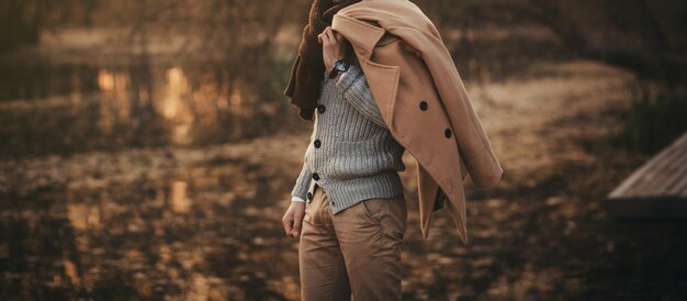 Uomo alla moda in maglione che posa nello spazio della copia del parco