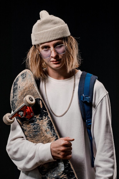 uomo alla moda in possesso di uno skateboard in Studio Primo piano di un sorridente skateboarder in posa