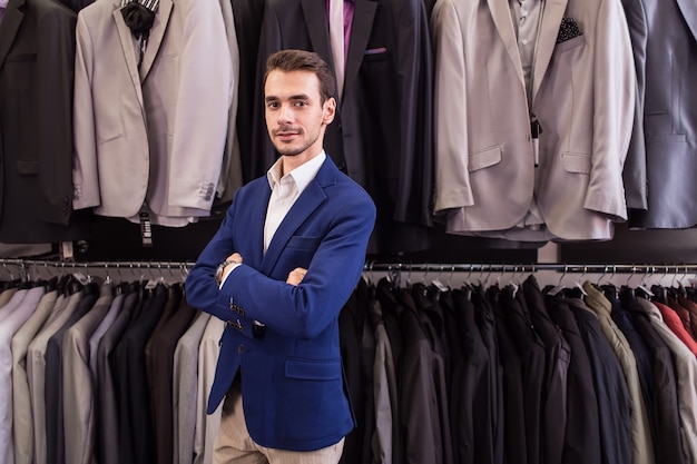 Uomo alla moda in una boutique di abbigliamento sullo sfondo di giacche