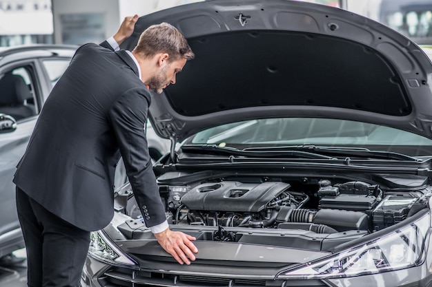 Uomo alla moda in vestito allo showroom di automobili