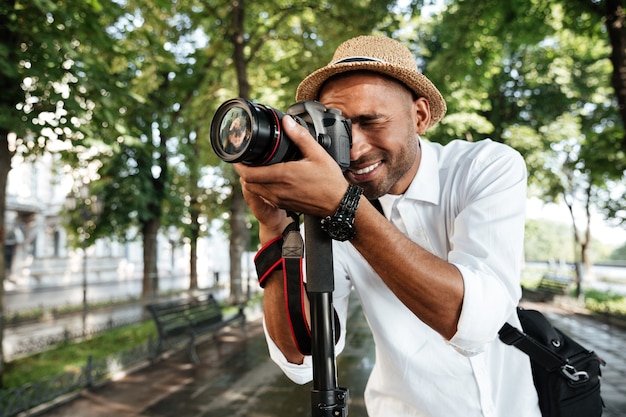 Uomo alla moda nel parco con il cappello che fa fotografie