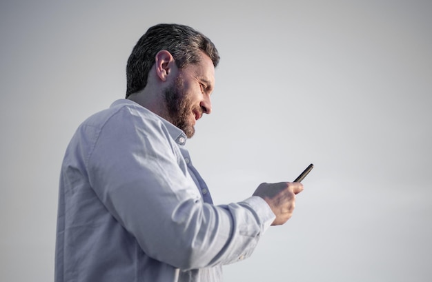 uomo allegro chatta sullo smartphone con un messaggio uomo che chatta sul telefono messaggistica smartphone comunicazione uomo chat sullo sfondo del cielo