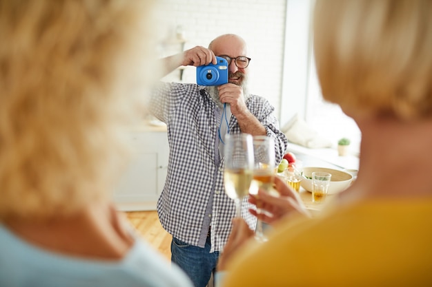 Uomo allegro che prende foto degli amici