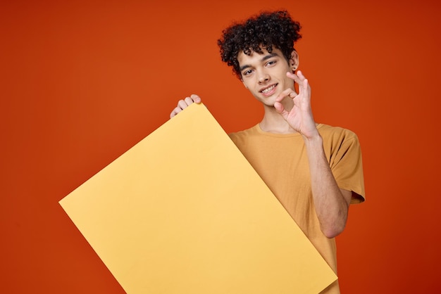 Uomo allegro con poster di capelli ricci in studio pubblicitario di mani