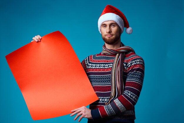Uomo allegro con un cappello da Babbo Natale che tiene in mano uno striscione vacanza sfondo blu