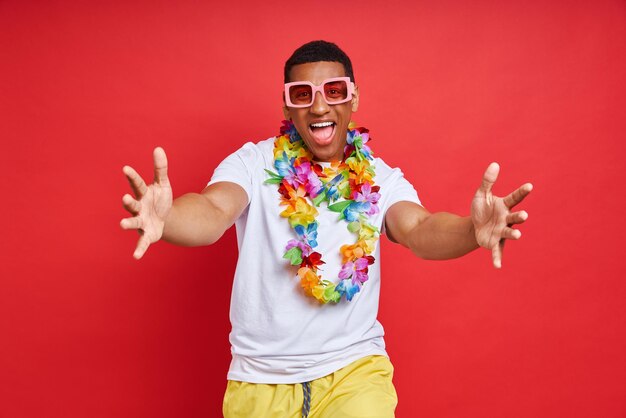 Uomo allegro con una collana hawaiana che ti accoglie in piedi sullo sfondo rosso