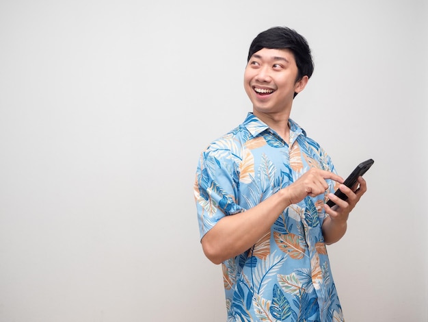Uomo allegro sorriso tenere lo smartphone per la prenotazione in vacanza girare il viso guardando lo spazio della copia
