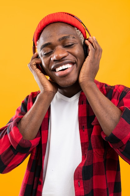 Uomo americano nero sorridente bello che gode della musica facendo uso delle cuffie