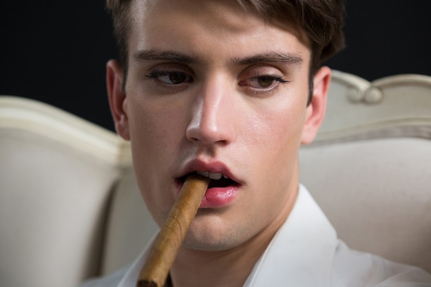Uomo androgino in posa con il sigaro in bocca