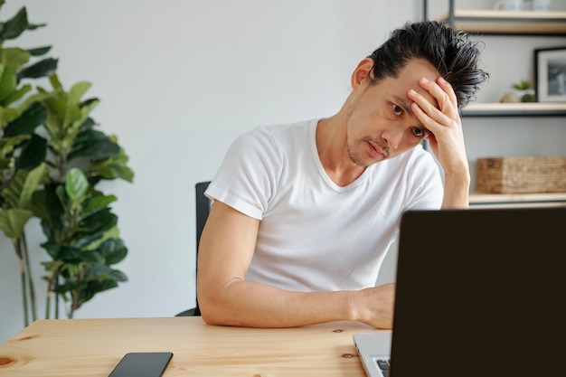 Uomo annoiato che lavora al computer portatile