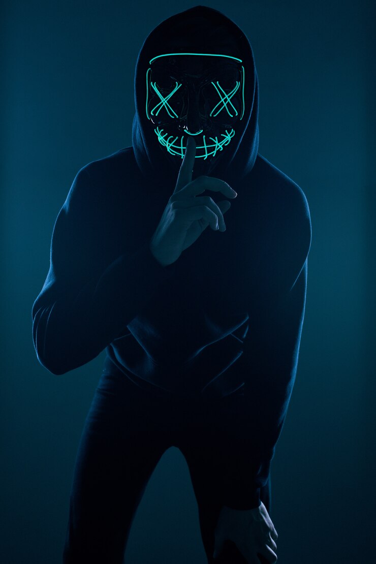Uomo anonimo con cappuccio nero che nasconde la faccia dietro una maschera al neon