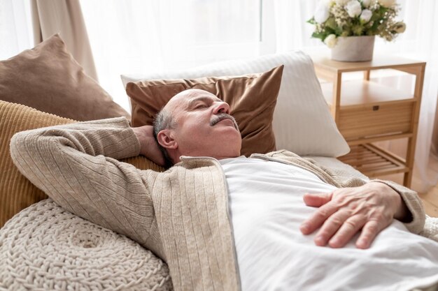Uomo anziano addormentato a letto a casa a sonnecchiare dopo colazione