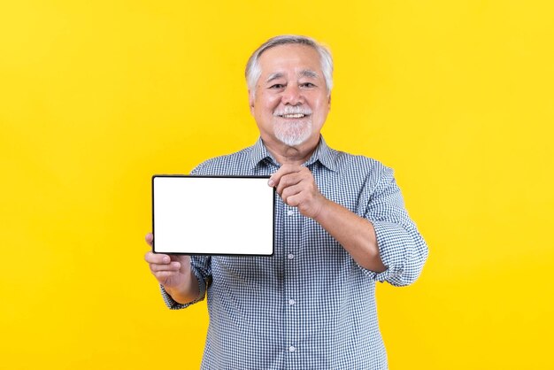 Uomo anziano asiatico che mostra il computer del telefono del tablet del telefono intelligente con lo spazio vuoto della copia dello schermo bianco dello schermo vuoto per il banner pubblicitario isolato su sfondo giallo Mock Up Image