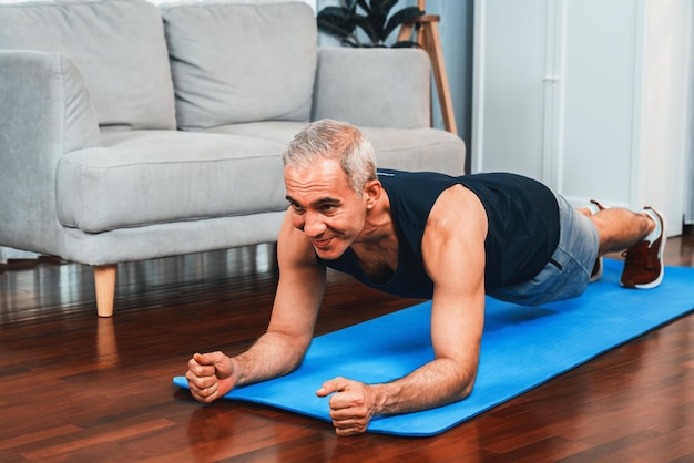 Uomo anziano atletico e sportivo che plancia sul tappetino per esercizi di fitness a casa esercizio come concetto di stile di vita sano e in forma dopo il pensionamento Peso
