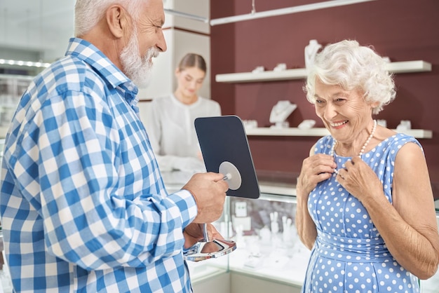 Uomo anziano attento che compra collana di lusso in gioielleria