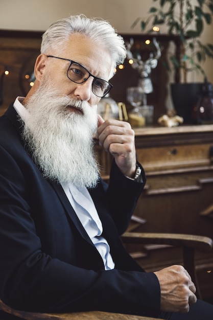 Uomo anziano barbuto elegante e bello che propone nello studio