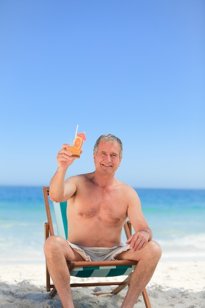 Uomo anziano che beve un cocktail sulla spiaggia