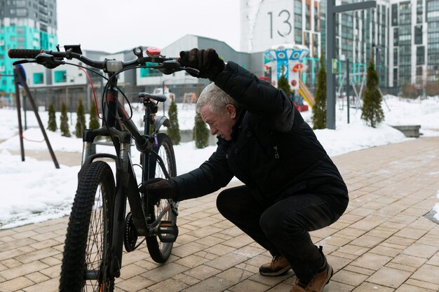 Uomo anziano che controlla la sua bicicletta per strada