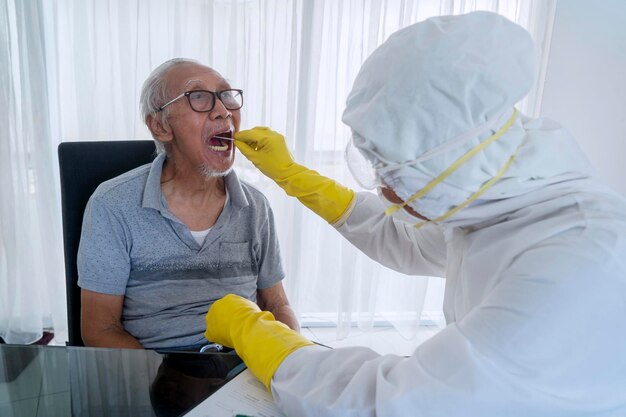 Uomo anziano che esegue il test del tampone con il lavoratore medico