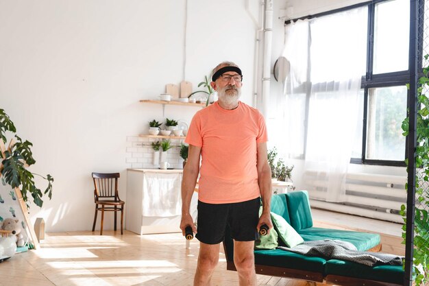 Uomo anziano che fa esercizi di fitness con classe virtuale e tiene i manubri benessere e benessere