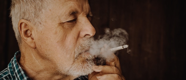 Uomo anziano che fuma sigaretta fuori, la dipendenza da sigarette, cattiva abitudine