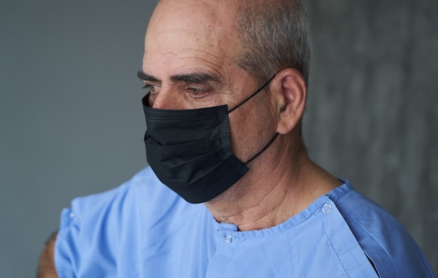 Uomo anziano che indossa la maschera per il viso durante coronavirus e epidemia di influenza