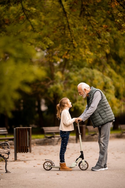 Uomo anziano che insegna a sua nipote come guidare il monopattino nel parco