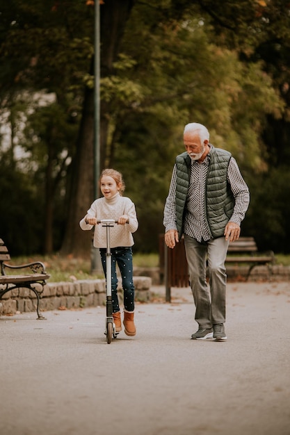 Uomo anziano che insegna a sua nipote come guidare il monopattino nel parco