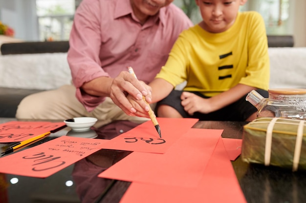 Uomo anziano che insegna al nipote a creare biglietti di auguri per il capodanno cinese