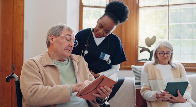 Uomo anziano che legge e infermiera che parla a casa con una discussione su un libro o con il supporto del personale infermieristico Assistenza agli anziani in pensione o persona che si rilassa in conversazione con il caregiver in salotto con un quaderno