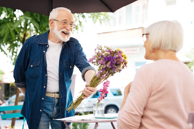 uomo anziano che offre fiori alla moglie