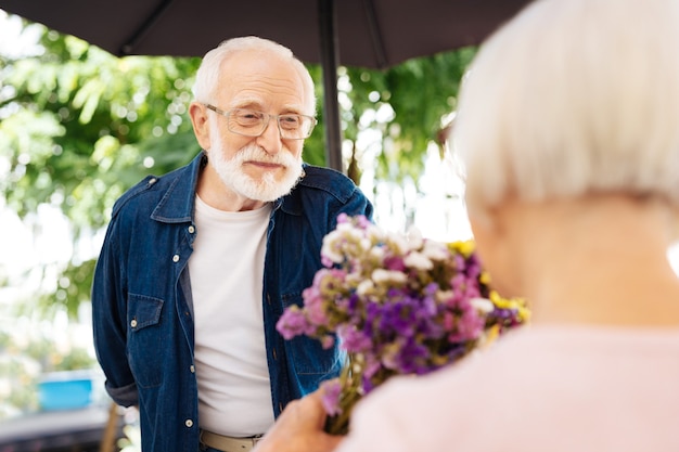 uomo anziano che offre fiori alla moglie