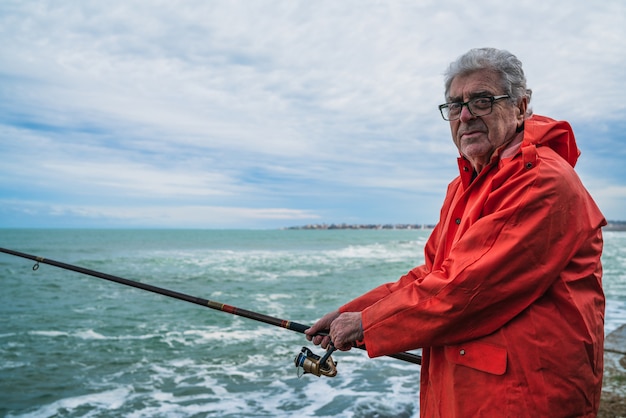 Uomo anziano che pesca nel mare.